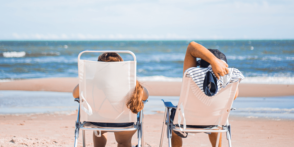 To mennesker i solstole på stranden